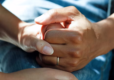 Two people's hands held together, one steadying the other.